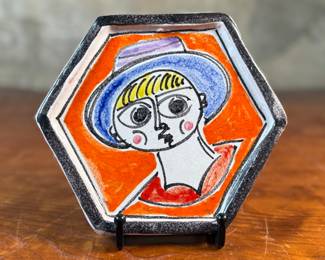 This lot features a stunning hand-painted hexagonal ceramic plate by listed Italian artist, Giovanni De Simone, circa 1960s. This piece measures, 6.25” H x 7” W. De Simone’s work is known for its vibrant colors and cubist drawing style, which was influenced by artists like Pablo Picasso. The company’s artistic tradition is continued by his daughter, Susanna De Simone. 
