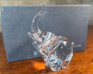 This lot features a Steuben crystal elephant with a raised trunk, designed by James Houston in 1964. Comes with a Steuben box for storage.
