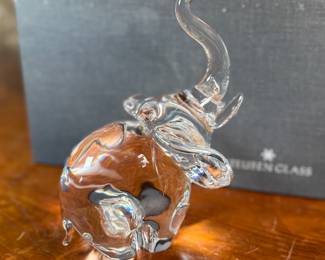 This lot features a Steuben crystal elephant with a raised trunk, designed by James Houston in 1964. Comes with a Steuben box for storage.
