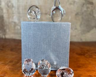 This lot features a collection of five (5) animal themed Steuben Glass sculptures, with five cases to accompany them. Steuben Glass is an American art glass company founded in Corning, New York, in 1903 by Frederick Carder. Originally known for colored glass, it shifted to brilliant clear crystal in the 1930s after being acquired by Corning Glass Works (now Corning Inc.) in 1918. The brand was sold in 2008, production ceased in 2011, and was reacquired by Corning Inc., which now oversees its production and sales through the Corning Museum of Glass.
