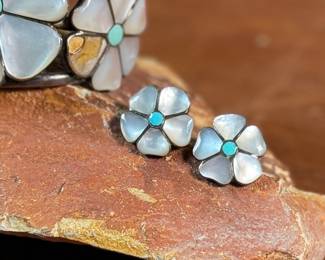 This lot features a vintage set of Zuni Native American jewelry including a bracelet cuff, earrings, and a ring made of sterling silver. The cuff has one inlay piece missing as shown in photos. The ring is a size 5, and the set has a total approx. weight of 57.05 grams. 

