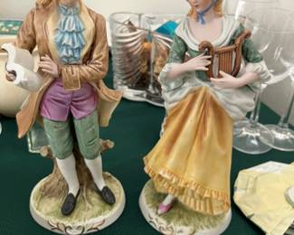 pair of vintage ceramic or porcelain figurines depicting a courting couple in colonial or Victorian-era attire