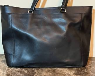 E76 - $85. TUMI Sinclair Tote Black Leather. Measures 20" x 11.5" tall (without handles) x 6" wide.