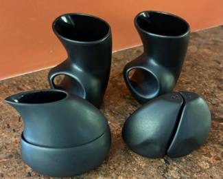 Salt and pepper shakers and tea cups by American artist Peter Saenger. The modernist work is made of black porcelain and is designed to fit together, creating a sculptural form.
