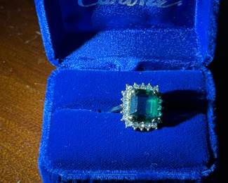 Emerald and Diamond Halo Ring
Exquisite emerald-cut green gemstone ring surrounded by sparkling diamonds, set in an elegant gold mount. Presented in a rich blue velvet box — timeless sophistication and classic beauty.