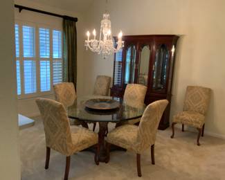 60” Round Glass Top table on ornate pedestal with six upholstered Parsons chairs.