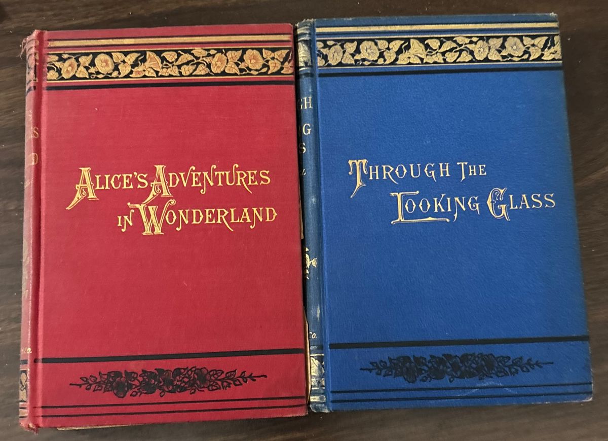 Two antique Lewis Carroll classics — Alice’s Adventures in Wonderland (1893) and Through the Looking-Glass (circa 1891), both illustrated by John Tenniel. Original gilt-decorated red and blue cloth covers. Printed in New York by Macmillan.