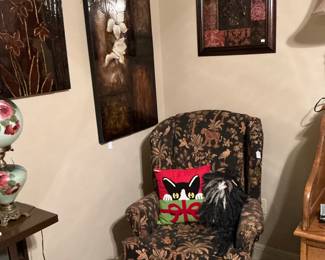 The fuzzy thing in the corner of the chair is a raggedy cat sitting next to a cat Christmas pillow