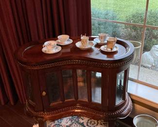 This is a kidney shaped drink cabinet, tea, cups, and saucers from various countries