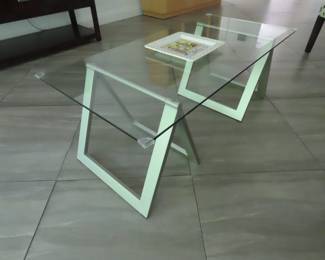 Glass coffee table on hinged stands.