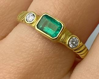 Size 6.5 natural emerald cut emerald with a diamond (E-F color, VS clarity) on either side, all bezel set in 18kt gold