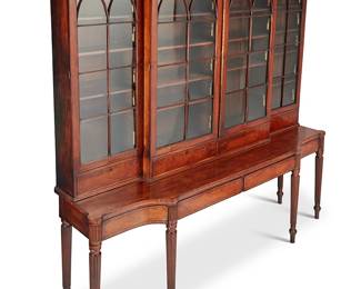 352
A George III mahogany breakfront on stand
Early 19th century elements
The three-piece upper console with architectural cornice above four astragal glazed cabinet doors with illuminated interior, each revealing adjustable shelves above a single drawer, set on a stand with four drawers, raised on fluted legs, electrified
5 pieces
Upper console: 70" H x 103.5" W x 23" D; Lower console: 38.25" H x 103" W x 27" D
Estimate: $1,000 - $1,500
