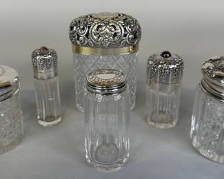 Collection Of Sterling Silver Mounted Cut Glass Vanity Jars And Bottles (6), note that these pieces do not compromise a matching set and includes a large cut crystal ovoid jar hallmarked at interior rims, H: 4 1/2 x 3 x d: 2 inches; a round cut crystal powder jar, stamped and numbered at rim of lid, H: 3 x dia: 2 1/2 inches; a round cut crystal jar with monogrammed hinge lid, hallmarked at rim, H: 3 1/2 x dia: 2 1/2 inches; small jar with floral engraved lid hallmarked at rim, H: 3 1/4 x dia: 1 1/2 inches; two small bottles of same pattern with inset semiprecious stones stamped at rims, H: 3 3/8 x dia: 1 inches and H: 3 1/4 x dia: 1 3/8 inches