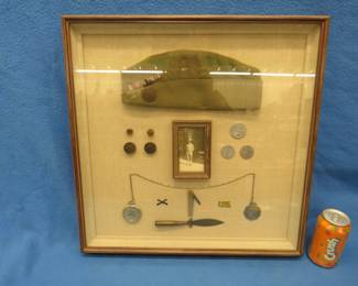 Lot 92. WW1 shadowbox. Fantastic collection which includes dog tags, cap, trench art knife, insignias, a Howard pocket watch, pocket knife, soldier photo.