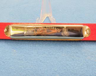 Lot 297. Carl Essbach double-octave "The Guards Band" tremolo harmonica in the key of C. Harp is in excellent condition, box is in poor condition.