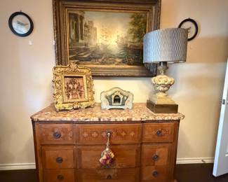 Neoclassical-style urn lamp with blue lampshade, Antique dresser/buffet with marble top, oil painting with large gold frame