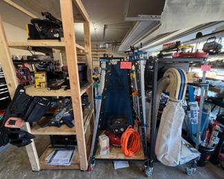 Wall dust collector on cart with wheels, clamp dolly with multiple large Rockler clamps, air compressor, handmade wooden cart with a variety of tools - sander, skill saw, tool belt
