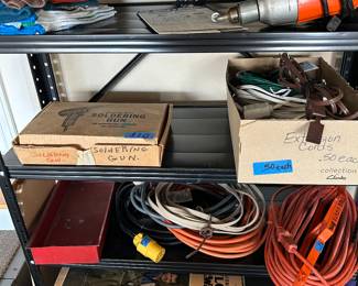 Lots of extension cords, indoors and outdoors. Soldering Gun on middle shelf, Big tarp on bottom shelf