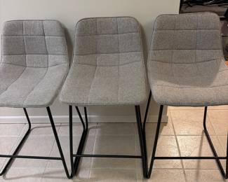 Three grey upholstered stools