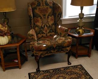 Beautiful arm chair with glass top end tables, large brass lamps with shades.