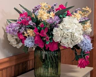 $15 Blown Green Glass Vase with Colorful Faux Flowers, with lobed sides, waisted neck and everted rim.
Height of vase: 8 in.; diameter: 5 ½ in.