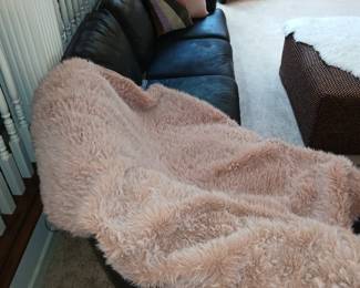 black leather curved corner sectional, pink faux sheepskin throw
