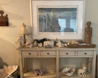 Soft cream console table with a large, framed beach scene print. The seashell collection includes a conk shell, 2 -driftwood pieces ,2-star fish, and 2- large clam shells and more.