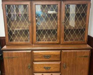 Classic China Hutch With Diamond-Pane Glass Doors
Two-piece build offers both display & storage: upper hutch with glass-front wood shelves, and a lower buffet with drawers & cabinets.Mid-Century Colonial Revival China Hutch (2-Piece)

1960s–70s colonial revival china hutch with diamond-pane glass doors. Two-piece build offers both display & storage: upper hutch with glass-front wood shelves, and a lower buffet with drawers & cabinets.Classic 

Complete hutch: 67.5" H x 61" W x 18" D
Top hutch: 35.5" H x 60" L x 12" D
Buffet base: 31.5" H x 60" L x 17.75" D
Features: 3 glass-front doors, 3 central drawers, 2 flanking cabinets with brass pulls & original hardware
Pickup Notes:
·   Local pick-up only. Please bring help to move; this is a two-piece unit for easier transport.
