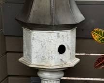 Dome birdhouse with a bell-shaped top and a square body with a circular opening, sits on a pedestal