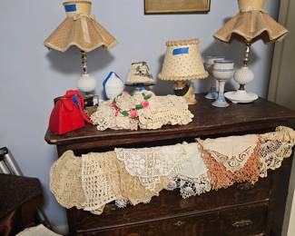 Lots of handwork... dollies, antique dresser with mirror, milk glass lamps.