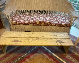 An antique wicker sofa teamed with a painted, rustic bench/table.