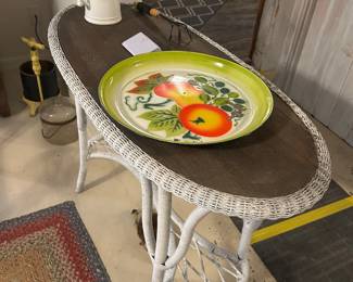 A wicker table topped by a decorative enamel tray and flowers.