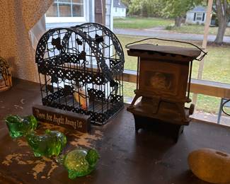 A vintage bird cage with glass frogs and an unusual frame.