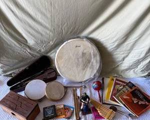 Vintage Musical Instruments Collection with Violin, Drum, Pan Flute, Maracas, Figurine, and Sheet Music