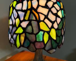 Small Tiffany-style stained glass accent lamp featuring a vibrant mosaic of jewel-toned glass pieces in shades of green, gold, lavender, and ruby.