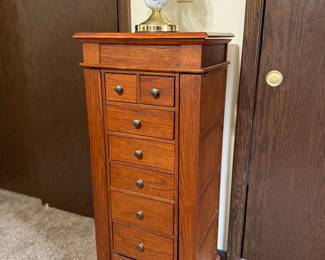Elegant tall jewelry cabinet featuring multiple drawers and brass knobs. Classic cherry finish with excellent storage for necklaces, rings, and accessories.