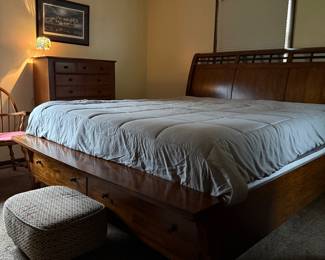 Elegant solid wood queen-size sleigh bed featuring rich warm finish, graceful curved headboard, and built-in under-bed drawers for convenient storage.