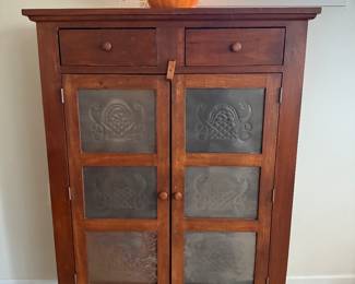 Classic country-style pie safe crafted from solid wood with two drawers and double cabinet doors featuring decorative punched tin inserts.