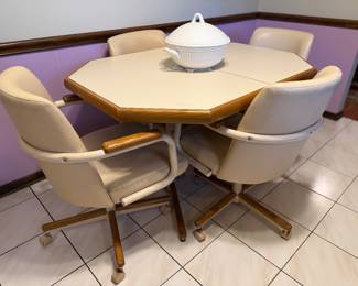 Vintage dining set featuring with octagonal laminate tabletop with a warm oak trim and matching cushioned rolling chairs.