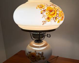 Vintage hurricane-style table lamp featuring a soft white glass shade with hand-painted yellow and amber floral designs.