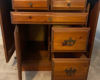 C6 - $50. Sewing Machine Table. Measures 33" wide x 24" deep x 28" tall. Each leaf adds 24". There is wear on the surface. Cabinet has 5 drawers, 1 door on hinges. (Needs minor work to reattach one leaf.)
