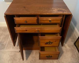 C6 - $50. Sewing Machine Table. Measures 33" wide x 24" deep x 28" tall. Each leaf adds 24". There is wear on the surface. Cabinet has 5 drawers, 1 door on hinges. (Needs minor work to reattach one leaf.)