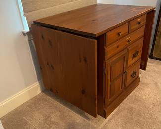 C6 - $50. Sewing Machine Table. Measures 33" wide x 24" deep x 28" tall. Each leaf adds 24". There is wear on the surface. Cabinet has 5 drawers, 1 door on hinges. (Needs minor work to reattach one leaf.)