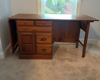 C6 - $50. Sewing Machine Table. Measures 33" wide x 24" deep x 28" tall. Each leaf adds 24". There is wear on the surface. Cabinet has 5 drawers, 1 door on hinges. (Needs minor work to reattach one leaf.)