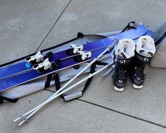 Skiing equipment. pair of Blizzard Black Pearl skis, Salomon ski boots, ski poles, and ski bags.