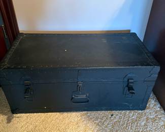 black antique trunk, possibly a steamer or foot locker, with metal hardware