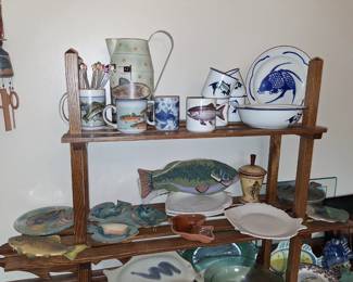 a collection of ceramic pottery, including plates, mugs, and pitchers, many of which are decorated with fish motifs. This type of pottery is often handmade