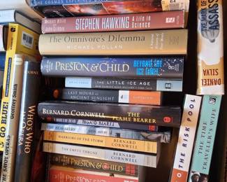 Authors visible include Stephen Hawking, Richard Dawkins, Bernard Cornwell, Preston & Child, and Daniel Silva.
Book titles visible include A Brief History of Time, The Greatest Show on Earth, The Omnivore's Dilemma, and The Codex.
The books appear to be a mix of fiction and non-fiction, with subjects ranging from science and history to thrillers