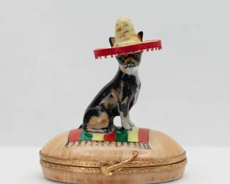 Artoria Limoges Porcelain Box Chihuahua Mexican Dog in Sombrero – Hand painted French Limoges porcelain oval shaped trinket box by Artoria Limoges, Chihuahua dog wearing a sombrero perched atop the lid. White glazed interior painted with a small colorful donkey. Artist's mark on underside of the base.