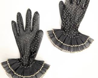 A vintage pair of black, sheer, polka-dotted gloves with a ruffled cuff